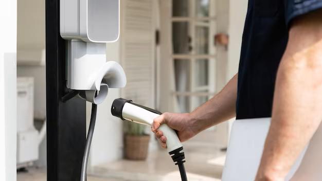 A close-up of a person plugging a Level 2 EV charger into a residential charging port, representing a common high-load home electrical upgrade.