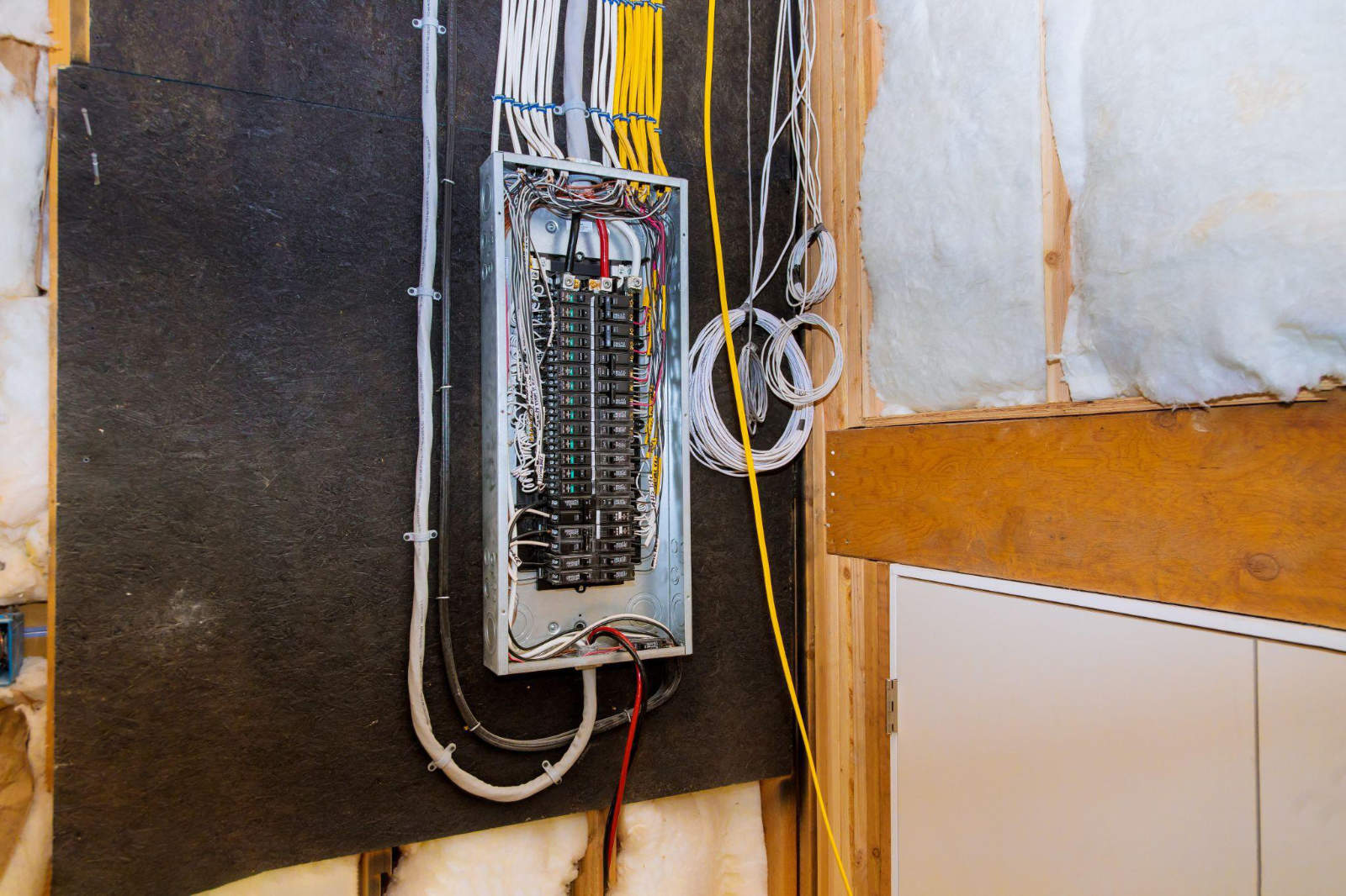 An open, modern residential electrical breaker panel with neatly organized new wiring, installed as part of a home renovation safety upgrade.