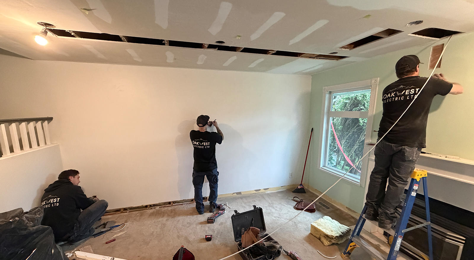 Oakwest Electric team working on interior wall wiring during a home renovation project.